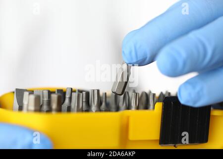Gloved craftsman pulls out screwdriver and screwdriver heads from yellow box Stock Photo