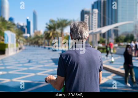 Senior man having a ride on electric scooter for transportation in a modern city environment back view Stock Photo