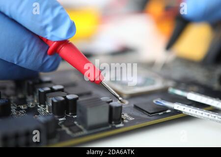 Gloved master holds probe over microcircuit closeup Stock Photo