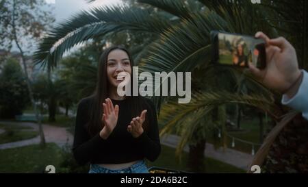 Young beautiful smiling fashion blogger woman making online new video blog, vlog, with her smartphone on nature background. Influencer speaking to cam Stock Photo