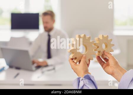 Close up of woman's hands holding round wooden figurines on the background of office worker. Stock Photo