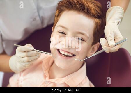 Smiling boy patient and positive woman dentist looking at camera in dental clinic Stock Photo
