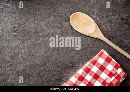 Wooden spoon and checkered tablecloth on black background Stock Photo