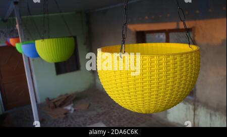Various color plastic hanging flower pot. Hanging multicolor plastic pots in the house. Stock Photo