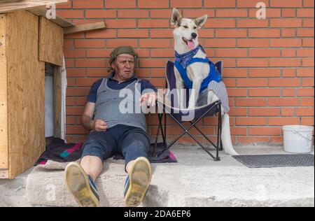 Two homeless fiends - man and dog resting while sitting on favourite places eagainst brick wall Stock Photo