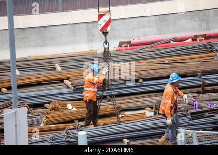 Steel reinforcement rebar being lifted by a crane on a Sydney construction site with construction workers helping,Australia Stock Photo