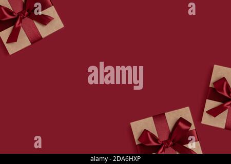 Frame made of gift boxes tied with ribbons on a red background with copy space. New Years composition. Stock Photo