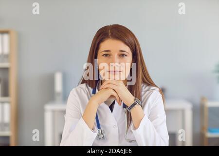 Head shot of competent understanding young doctor looking at camera and listening to you Stock Photo