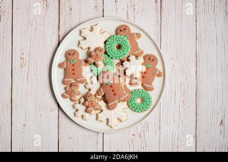 Plate of decorated Christmas gingerbread cookies gingerbread man with snowflakes and other cookies on a textured wood surface Stock Photo