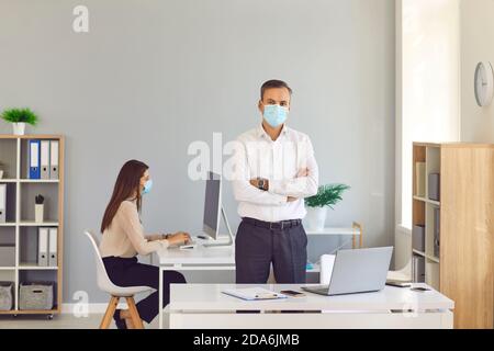 Male manager in a protective mask at work due to the epidemiological situation in the world. Stock Photo