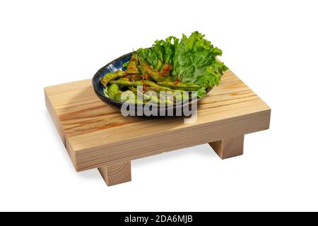 Fried Edamame with garlic and chilies on wooden board. Isolated on white background. Stock Photo