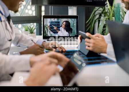 Cropped image of multiracial doctors using laptop for video conference with African female colleague, discussing CT scan results and making notes on Stock Photo