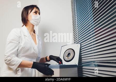 High angle view of a beautiful female chemist looking at some blood samples out of a centrifuge in a laboratory. Stock Photo
