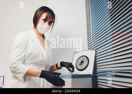 High angle view of a beautiful female chemist looking at some blood samples out of a centrifuge in a laboratory. Stock Photo