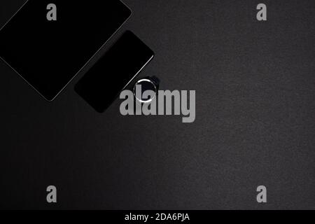 Overhead shot of a smartwatch, smartphone and a tablet on a black background. Wireless technology concept. Horizontal photography. Copyspace Stock Photo