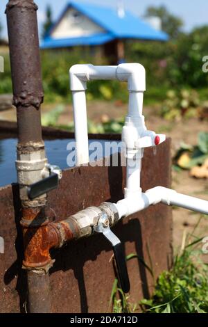 Connection of plastic pipes to the pump and water storage tank. Pumping water using a homemade plumbing. Stock Photo