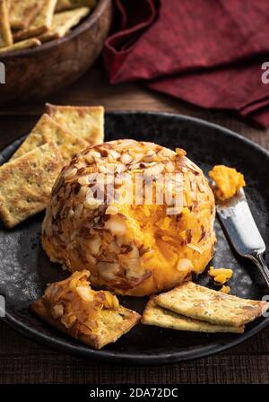 Cheddar cheese ball and crackers on a black plate Stock Photo