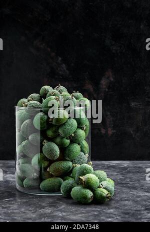 green feijoa fruit in glass vase on a black background Stock Photo