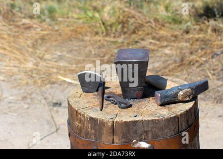 The old tools of a blacksmith on large wooden stump Stock Photo