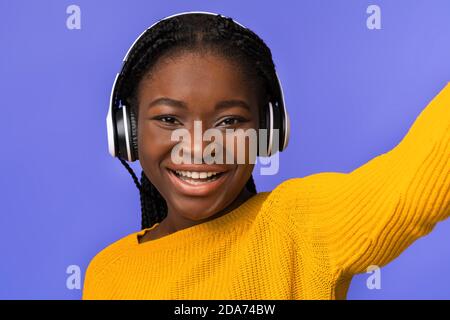 Selfie Fun. Cheerful Black Lady In Wireless Headphones Taking Self-Portrait, Closeup Shot Stock Photo