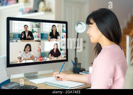 Asian business woman talking to her colleagues about plan in video conference. Multiethnic business team using computer for a online meeting in video Stock Photo
