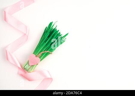 Satin pink ribbon bouquet with a heart on a light background. Stock Photo