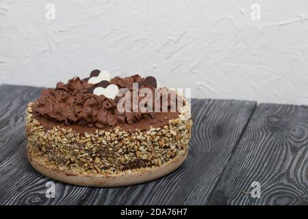 Chocolate cake with cream and peanuts. Decorated with chocolate hearts. On pine boards. Stock Photo