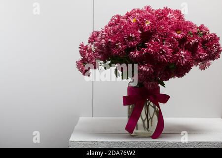 Bouquet of red chrysanthemums on a white table surface. Stock Photo