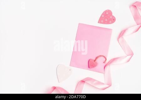 Hearts, ribbon and pink envelope on a light background. Stock Photo