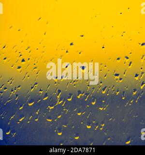 Window in raindrops closeup. Water drops on glass. Orange blue background Stock Photo