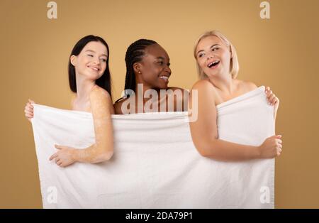 Beauty And Spa. Body Positive Multi-Ethnic Women Hiding Behind Bath Towel Stock Photo