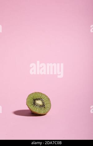 Around freshly squeezed juice kiwi  slice on a bright pink colored background. Stock Photo