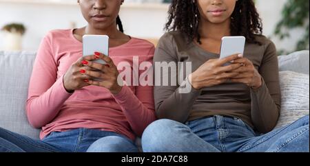 Unrecognizable black women using mobile phones at home Stock Photo