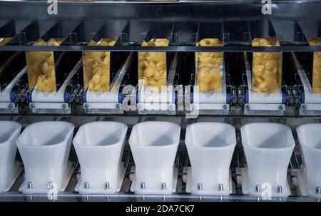 Dry pasta on automatic combination weighers. Multihead weighers machine in food industry. Stock Photo