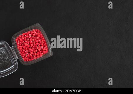 Frozen berries in a transparent container on a black background. Frozen red currant. Copy space, view from above. Stock Photo