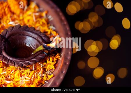Happy Diwali - Diya oil clay lamp beautifully decorated with orange flowers on the festive occasion of deepawali. Background for Hindu religious ritua Stock Photo