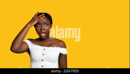 Oh No. Shocked black woman looking away and touching head in disbelief Stock Photo