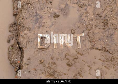 the word mud imprinted in wet dirt road surface - close-up with selective focus Stock Photo