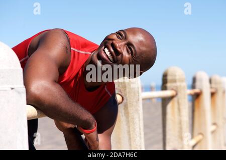 Close up portrait of cheerful young sports man leaning on railing outdoors Stock Photo