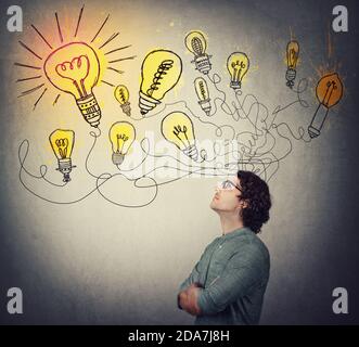 Creative businessman, thinking of great ideas, looking at bright lightbulbs on the wall. Business worker search for solutions to solve the problems, g Stock Photo