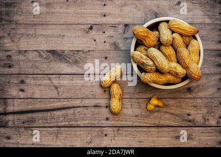 Bowl of peanuts in the shells with a wooden background, copy space and top view Stock Photo