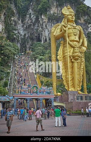 Kuala Lumpur, Malaysia, February 2016. Tourists at the entrance stairs to the Batu caves with the statue of Murugan in front. Stock Photo