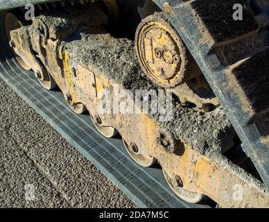 closeup of the mud caked undercarriage and track of a small bulldozer at a construction site Stock Photo