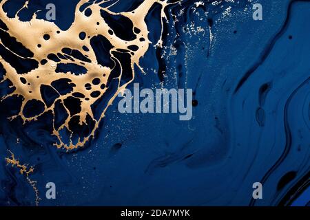 Golden abstract spot on blue flowing background. Marble background or texture. Fluid Art Stock Photo