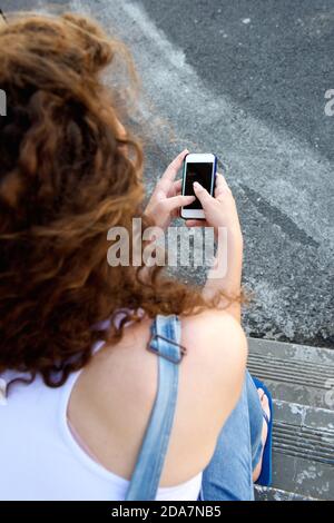 Portrait of young girl from behind holding cellphone and texting Stock Photo