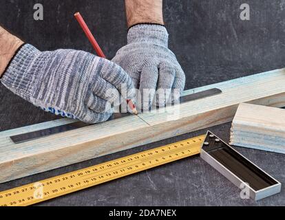 Woodwork and furniture making concept. Carpenter in the workshop makes markings of wooden workpieces Stock Photo