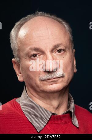 Sad and tired old man. Portrait of an elderly emotional man on a dark background in the studio Stock Photo