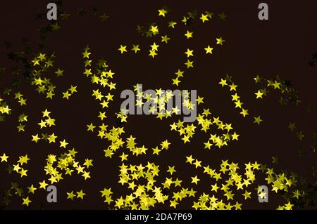 Golden stars on black background. Christmas festive background. Flat lay, top view. Selective focus. Stock Photo
