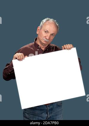 Senior man holds a blank board. Elder man holding blank canvas. Blank poster for text message or advertisement. Stock Photo