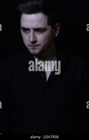 Man in front of black background looking at the ground. Stock Photo